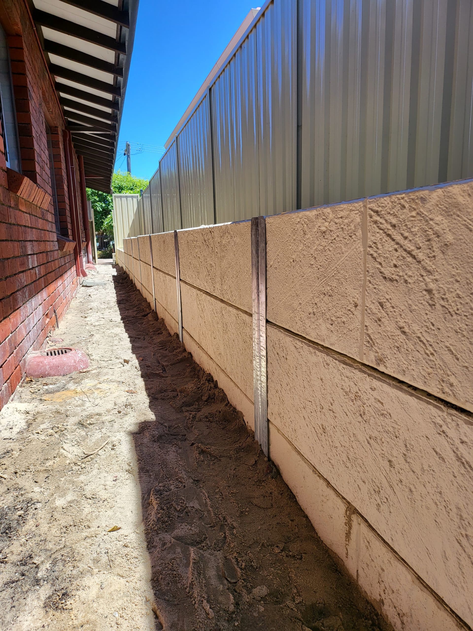 post and panel retaining wall installation + colorbond fence