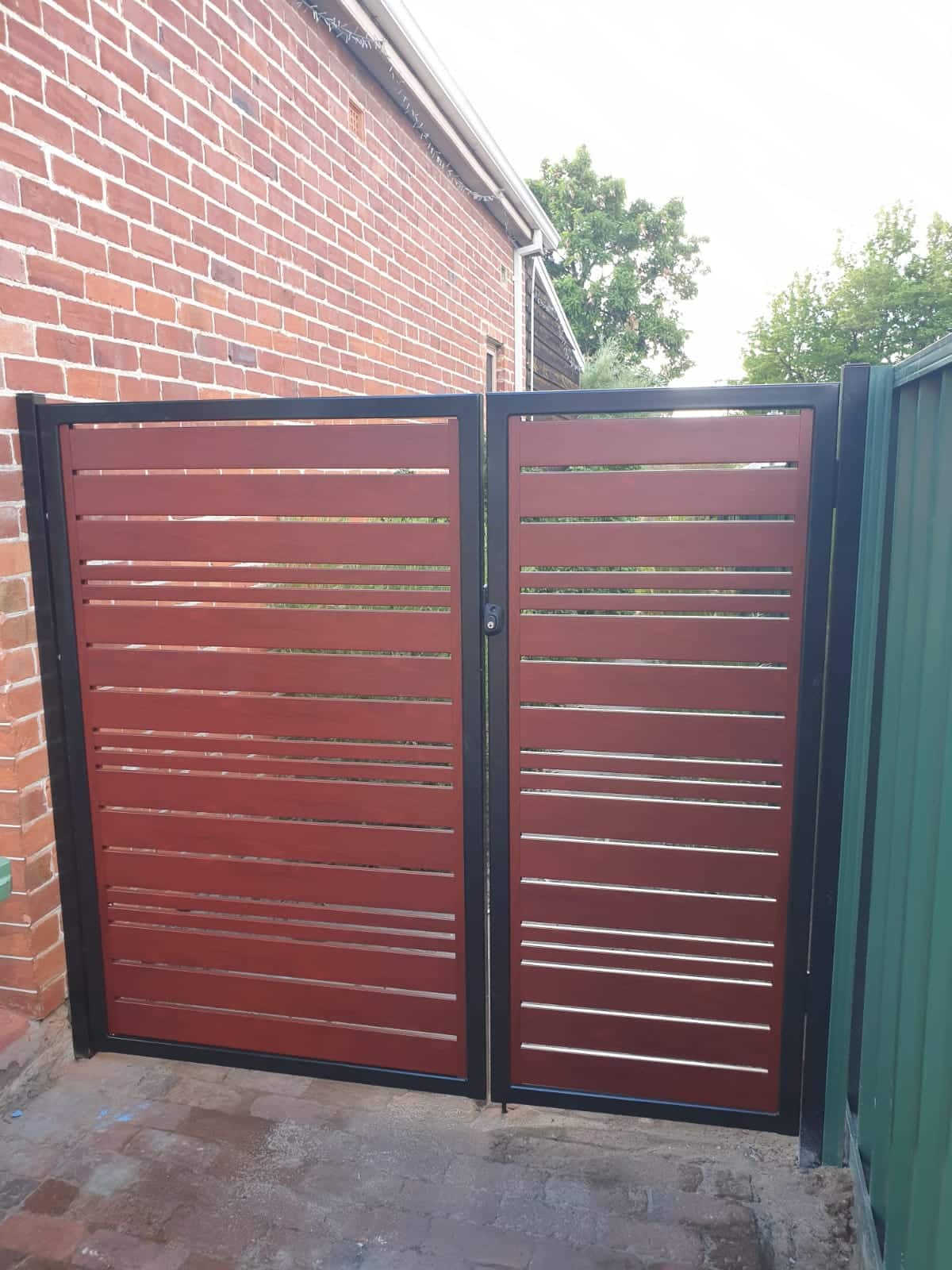A red slat gate installed for a property in Perth, providing a secure and stylish entrance. The gate features evenly spaced horizontal slats made of durable materials such as aluminum, and is powder-coated in a bold red color that adds a touch of personality to the property. The gate can be customized to fit any size or shape of the entrance, and is designed to provide both privacy and visibility. With its low maintenance and long-lasting durability, a slat red gate is a popular choice for residential and commercial properties in Perth